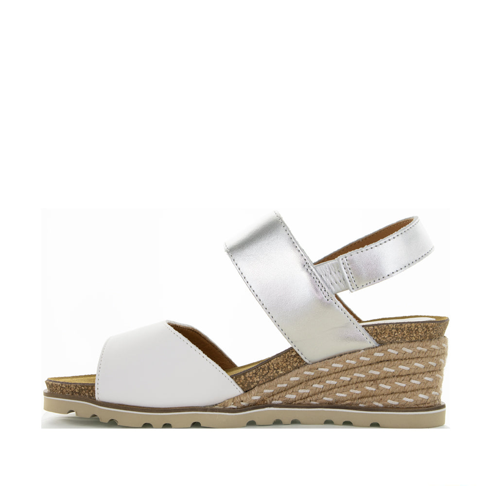 Le Sansa Evita white and silver sandals with thin straps and low heel, stylishly displayed on a neutral background.