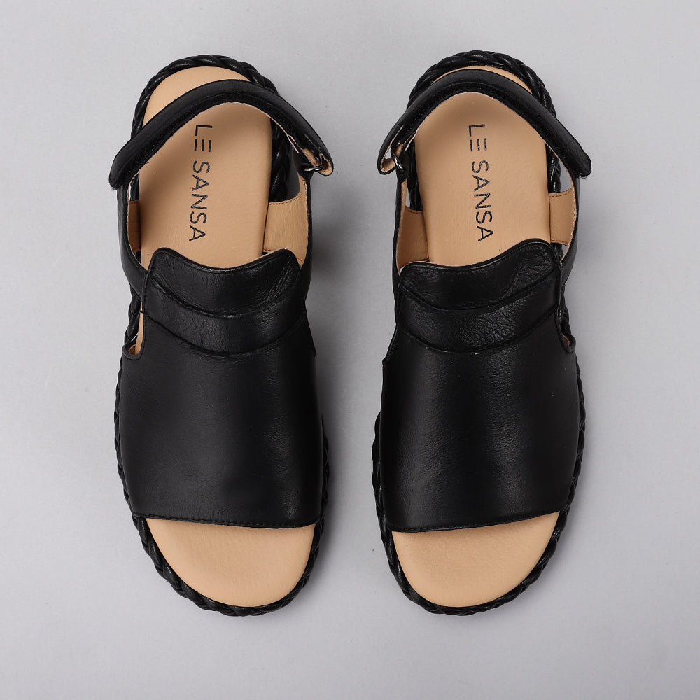 Le Sansa Emmeline black sandals with ankle straps and open toes, featuring stylish leather design and comfortable flat sole.