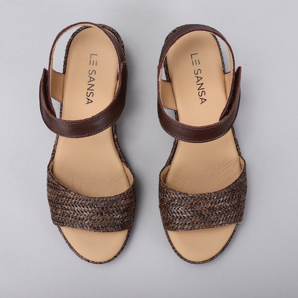 Le Sansa Pilia chocolate sandals with leather straps and cushioned soles, displayed on a neutral background.