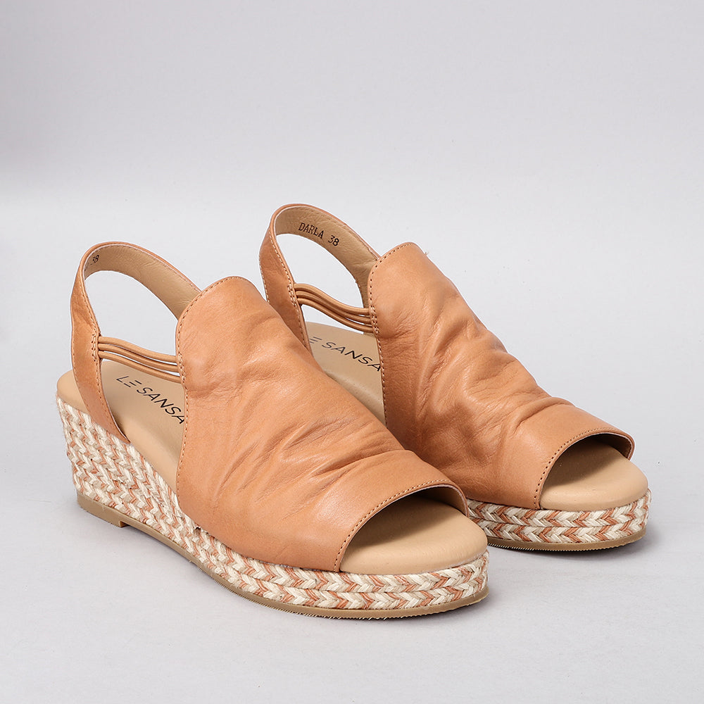Le Sansa Darla tan sandals with ankle straps and flat soles, featuring a stylish, minimalist design perfect for casual wear.