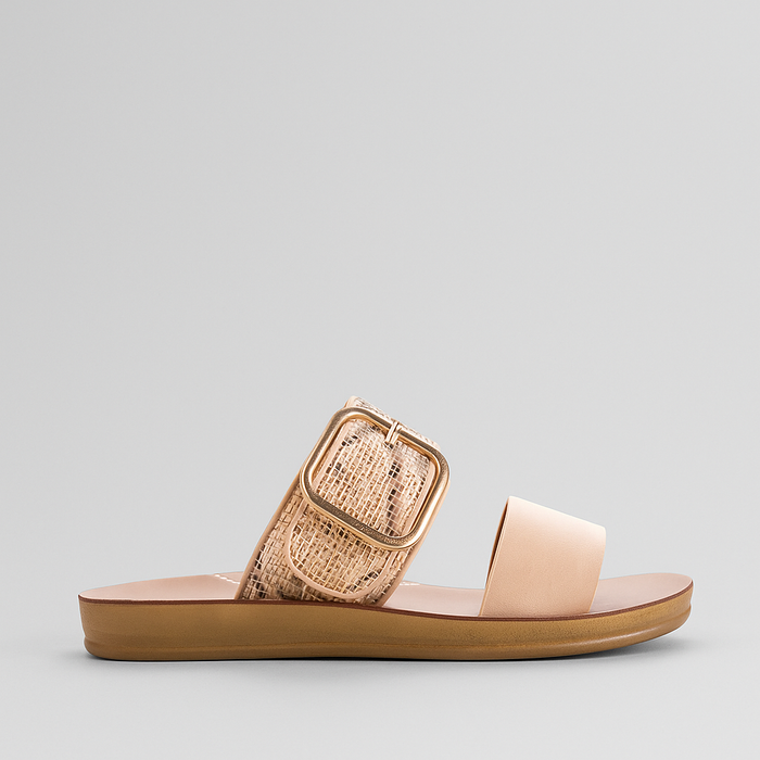 Los Cabos Doti taupe multi flats displayed on a stylish sandal stand with a textured background.