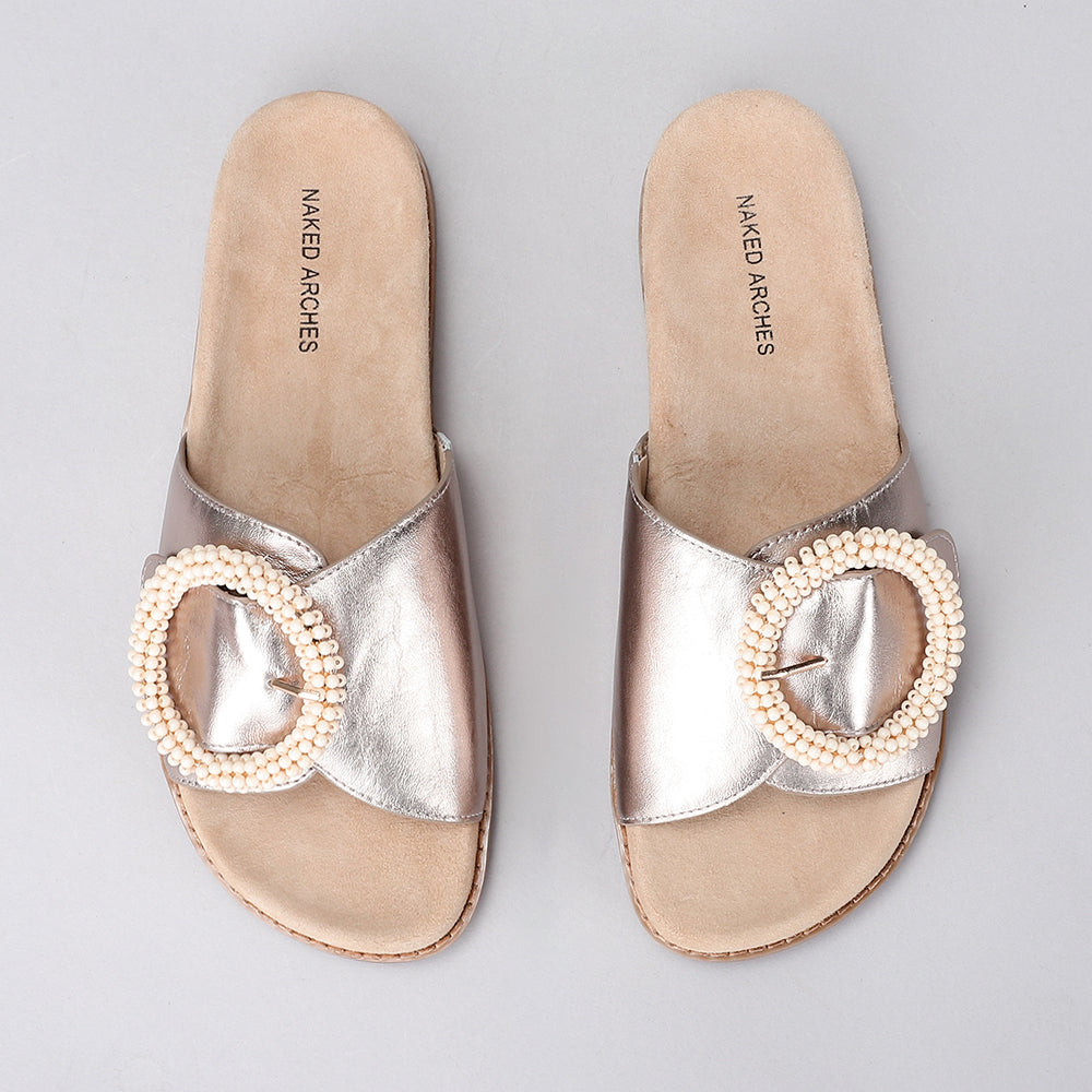 Naked Arches Zoya Champagne slip-on shoes with a sleek design and neutral champagne color, displayed on a white background.