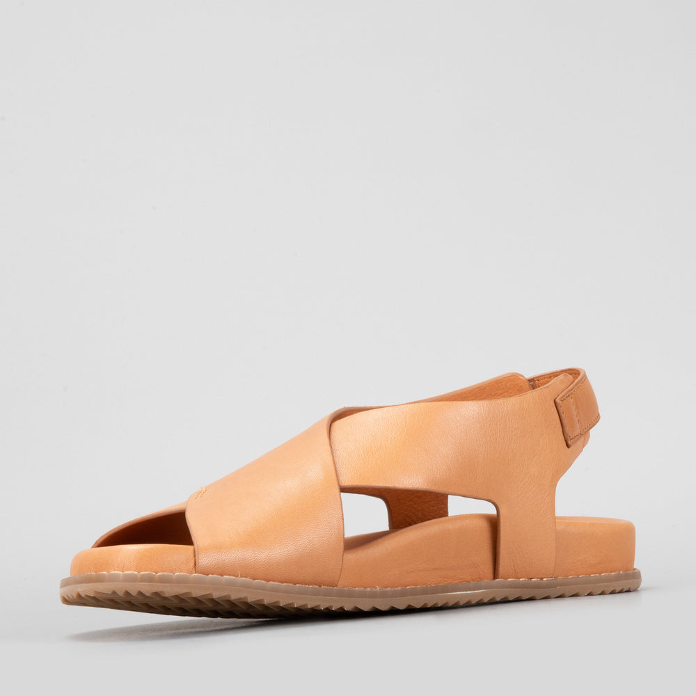 Naked Arches Zigilia Tan sandals with brown leather straps and cushioned footbed on a neutral background.