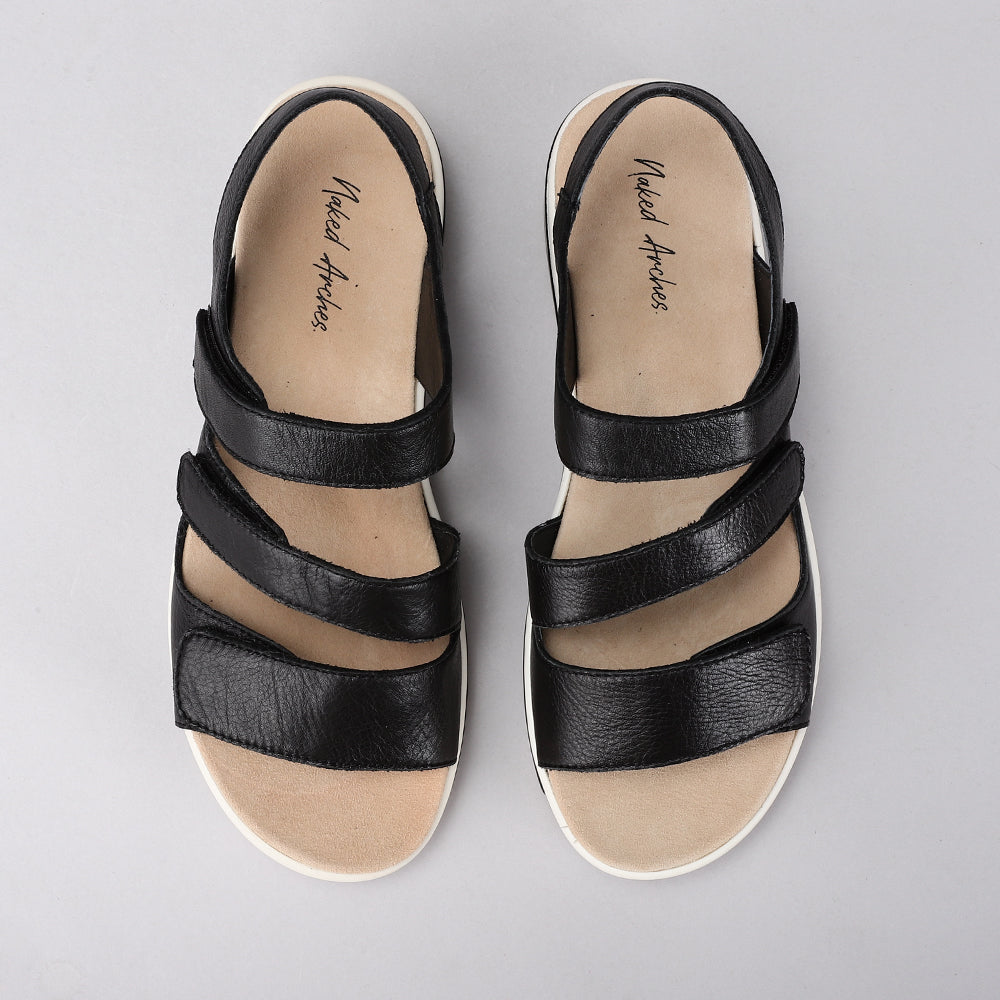 NAKED ARCHES Holiday Black sandals with strappy black leather design and flat sole, stylish footwear for casual summer wear.
