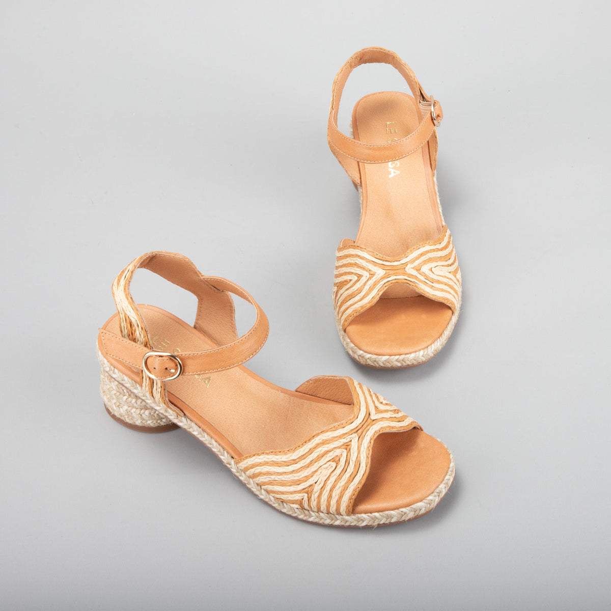 Le Sansa Alys tan and beige sandals with ankle straps and open toe design, displayed on a neutral background.