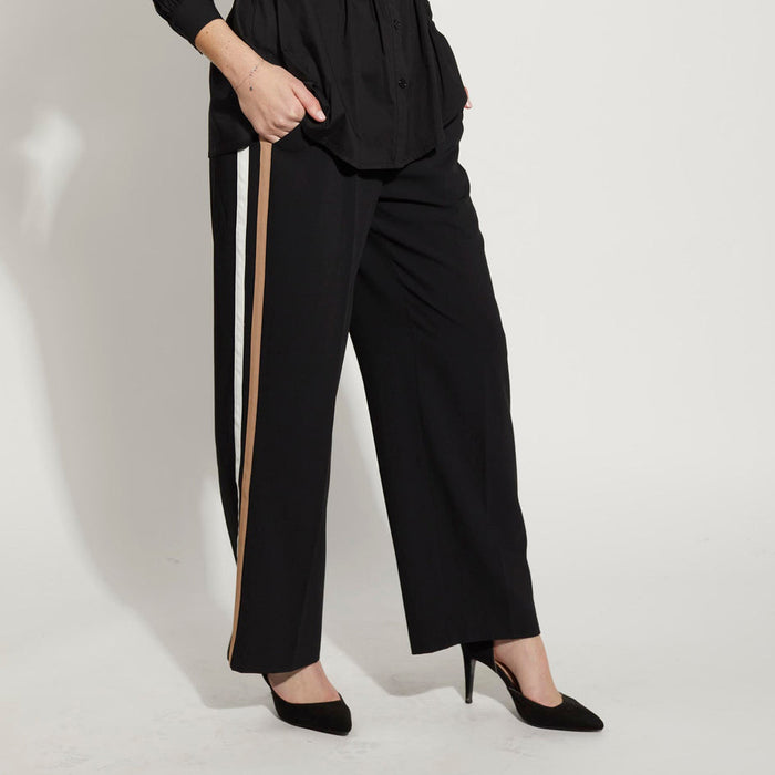 Black and tan Drama The Label Forde pants, tailored trousers with a sleek fit, shown with a black twisted shirt.