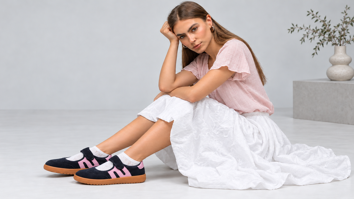 A model in an oversized brown shirt and wide-leg denim, against a concrete wall