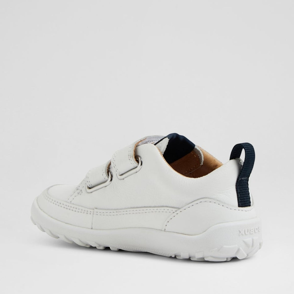 Baby sneakers by Bobux in white and navy with soft soles and Velcro straps, designed for comfortable, stylish toddler footwear.