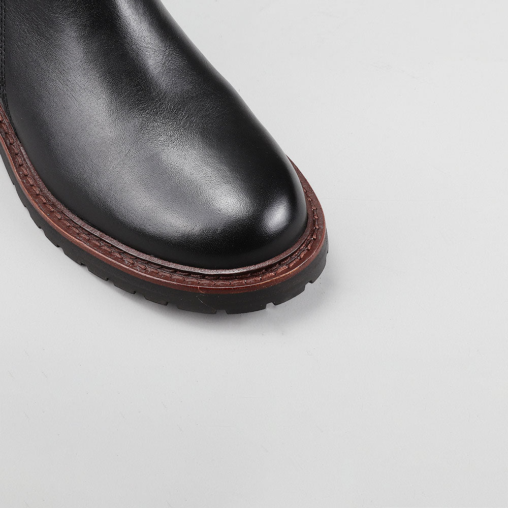Close-up of Le Sansa Cayla black boots showing sleek leather material and stylish ankle design.