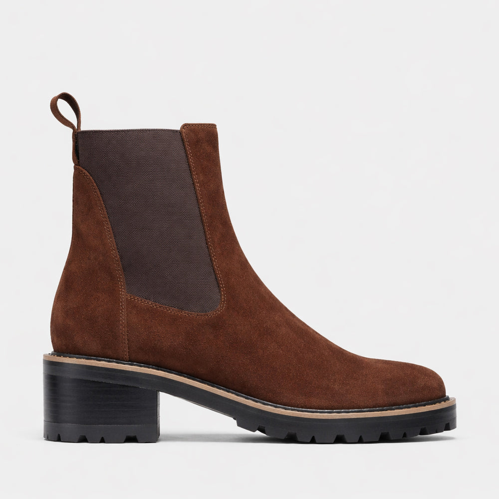 Eos Linear Chestnut Suede Boots displayed on a model, featuring a sleek design and ankle height in natural light.