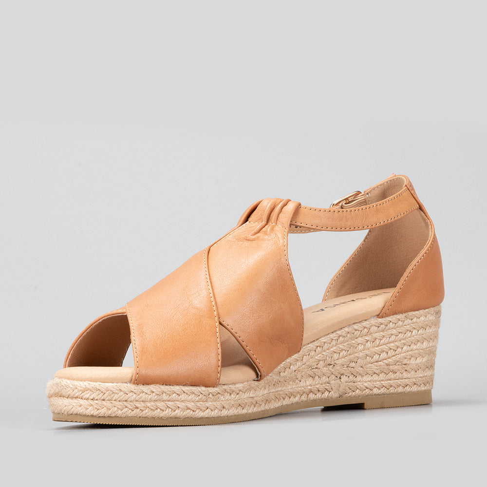 Le Sansa Pernia tan sandals featuring a stylish open-toe design with ankle straps and a flat sole.
