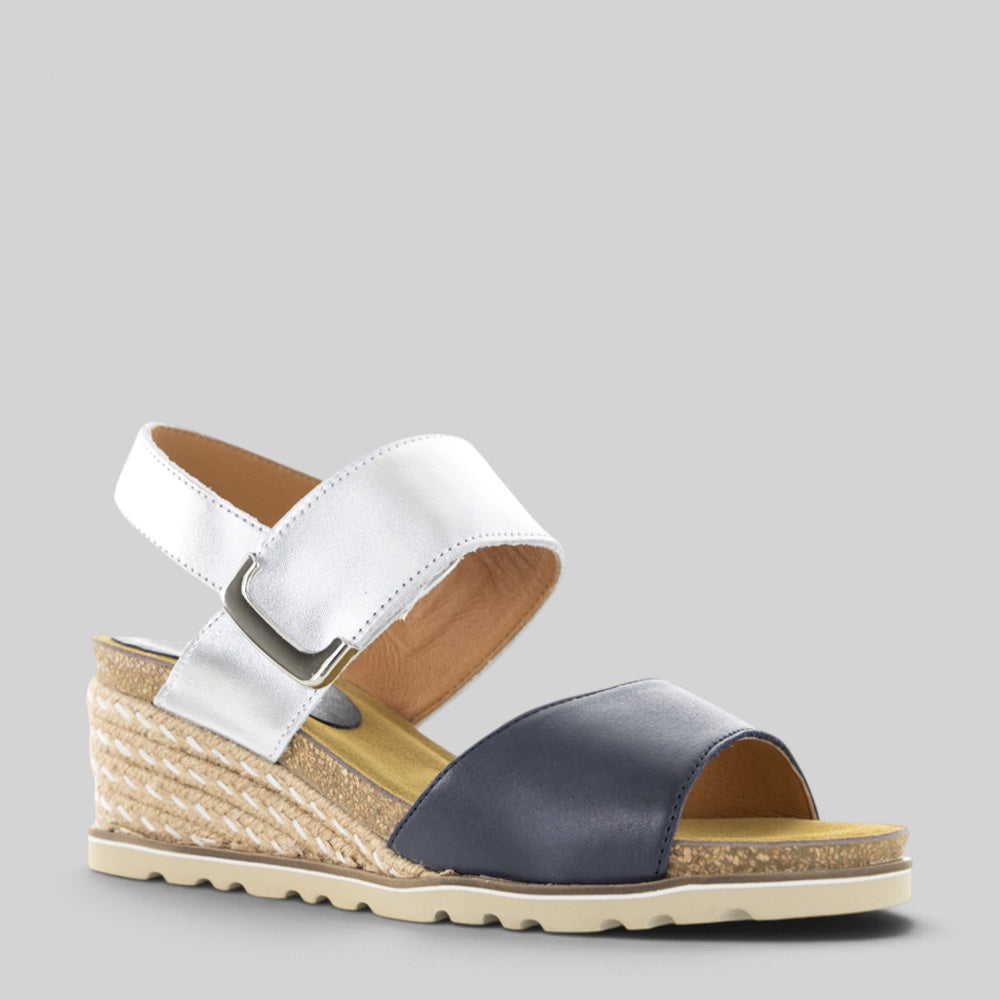 Le Sansa Evita navy silver sandals with ankle straps and metallic accents, displayed on a neutral background.