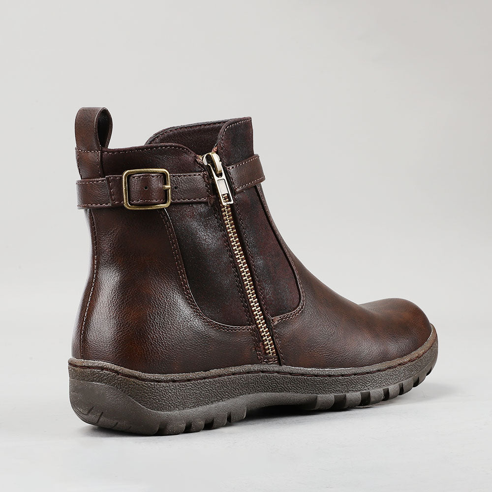 CC Resorts grey chocolate boots with a stylish ankle design, shown on a model's feet in a casual outdoor setting.
