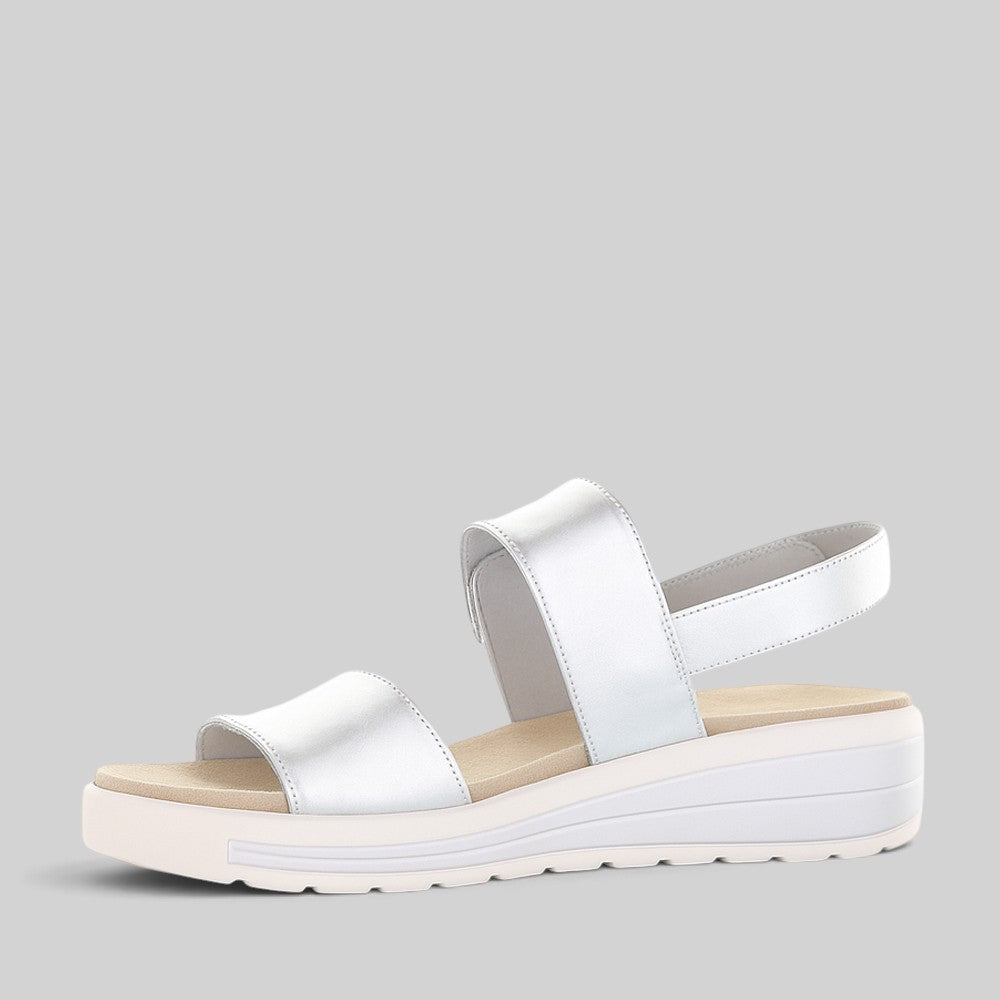 Silver Naked Arches Hanza sandals with strappy design and flat sole, displayed on a neutral background.