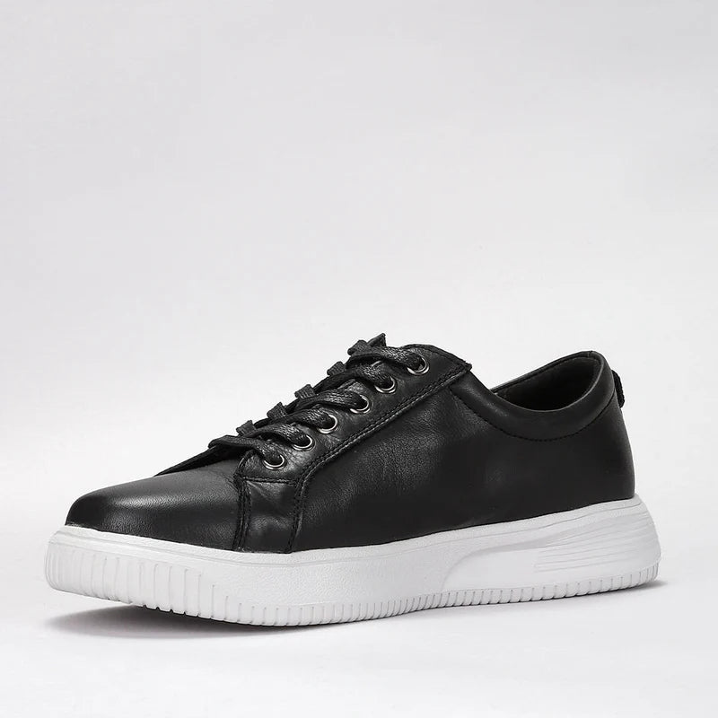 Black Naked Arches Nelly sneakers with sleek design and white sole, showcased in a close-up image.