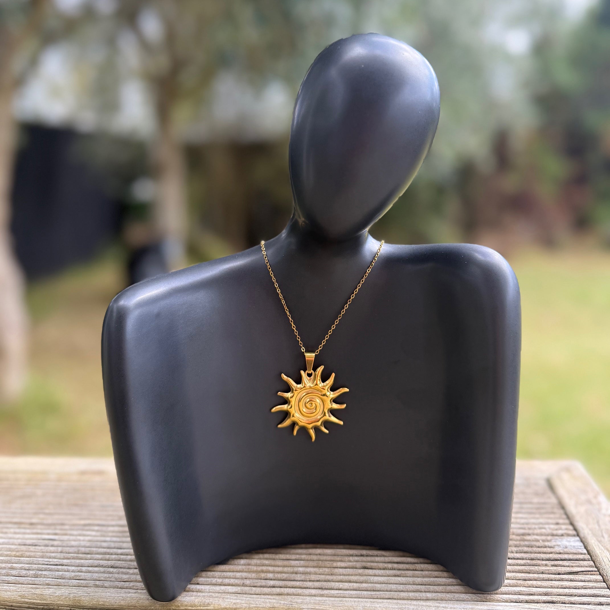 Gold spiral sun pendant necklace from Zeke Collection featuring a detailed sun design on a sleek chain.