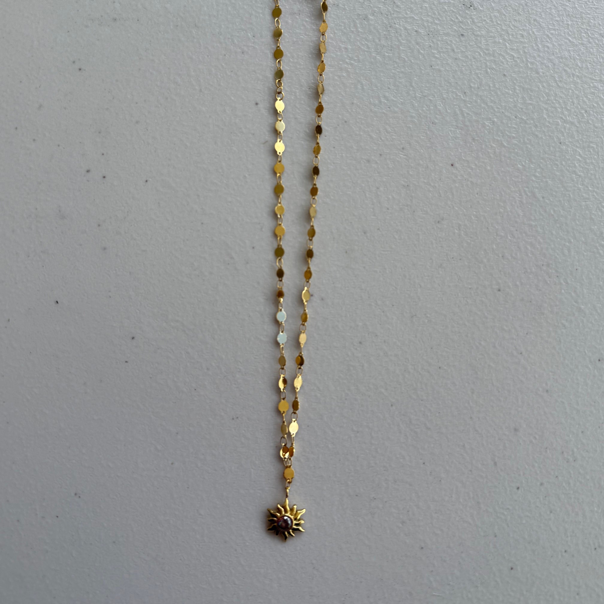 Golden Sun Charm Necklace from Zeke Collection featuring a pendant with a detailed sun design on a delicate chain.