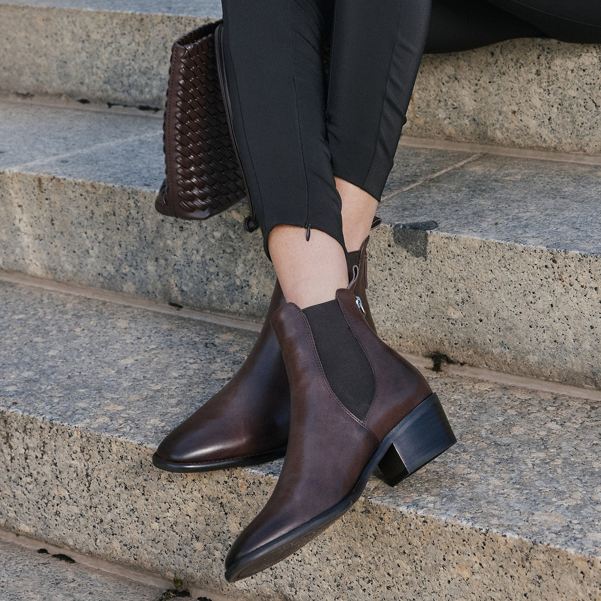 Eos Ila Chestnut boots with crossed legs, showcasing stylish brown leather footwear from the front view.