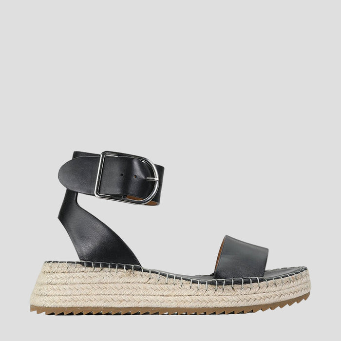 Eos Larah black sandals outdoors, featuring open-toe design and ankle straps, stylishly displayed on a natural setting.