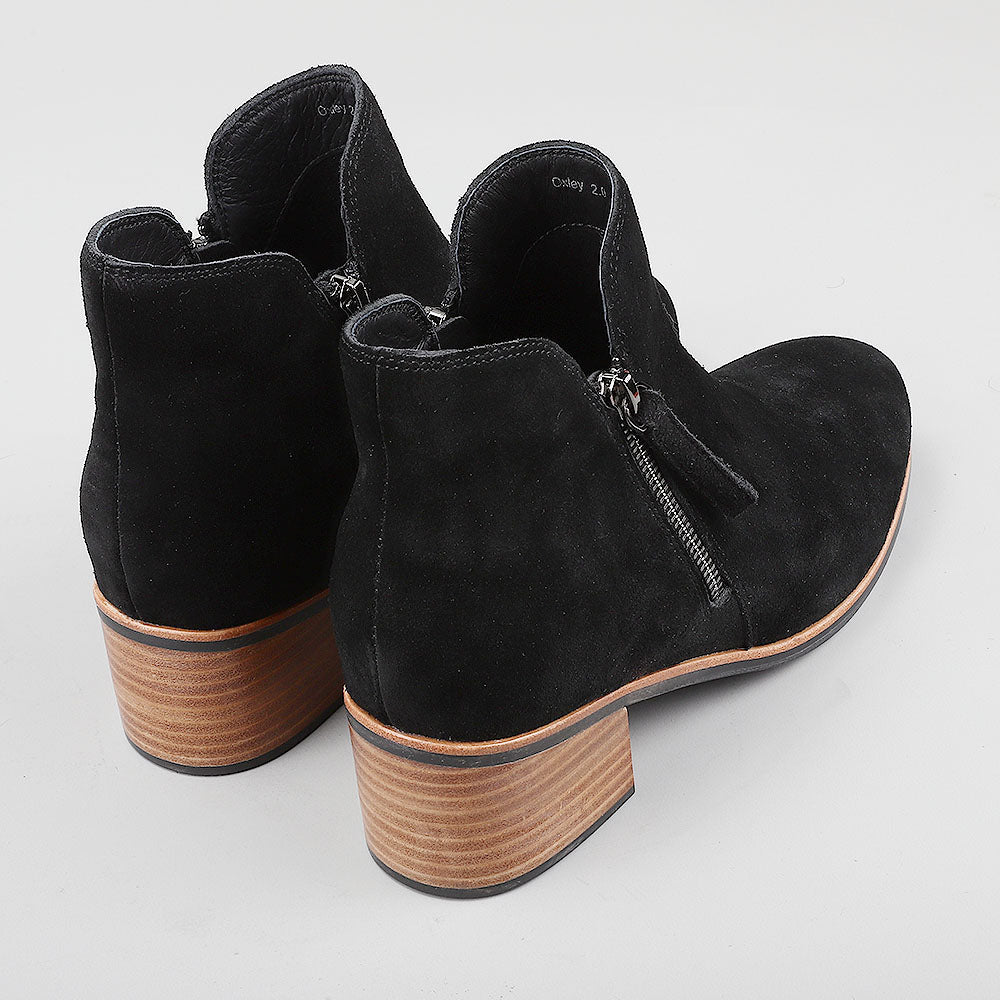 Pair of Naked Arches Oxley black suede boots showing the back view with sleek design and sturdy heel.