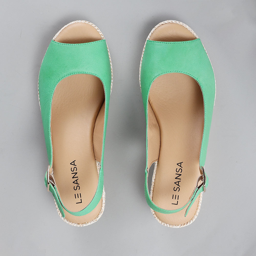 Le Sansa Petunia Fern Green sandals featuring open-toe design and ankle straps, crafted with soft green leather for stylish comfort.