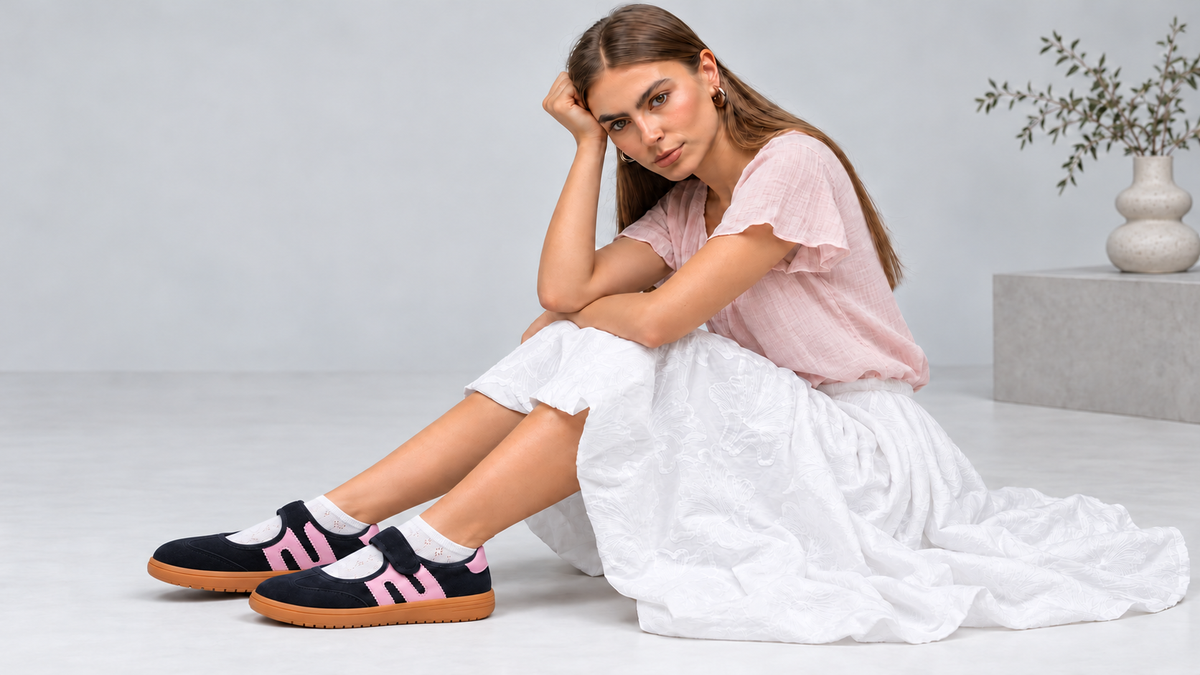 A model in an oversized brown shirt and wide-leg denim, against a concrete wall