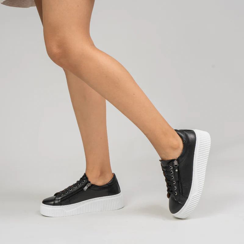Black Le Sansa Palmer sneakers with sleek design and white soles, shown from a side angle.