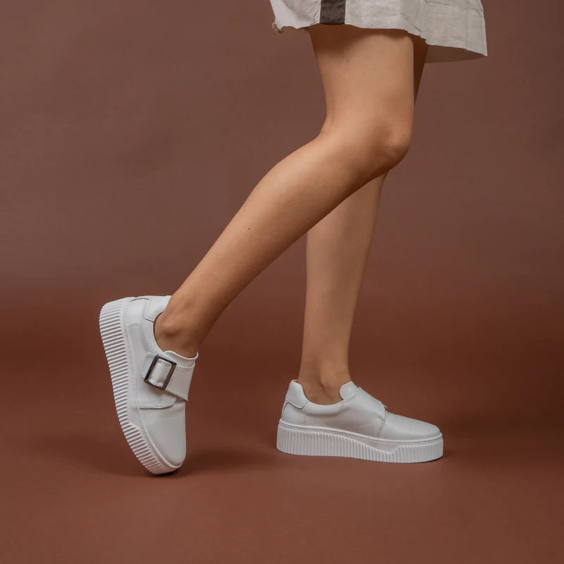 White Le Sansa Philia sneakers with sleek design and white laces, displayed on a neutral background.