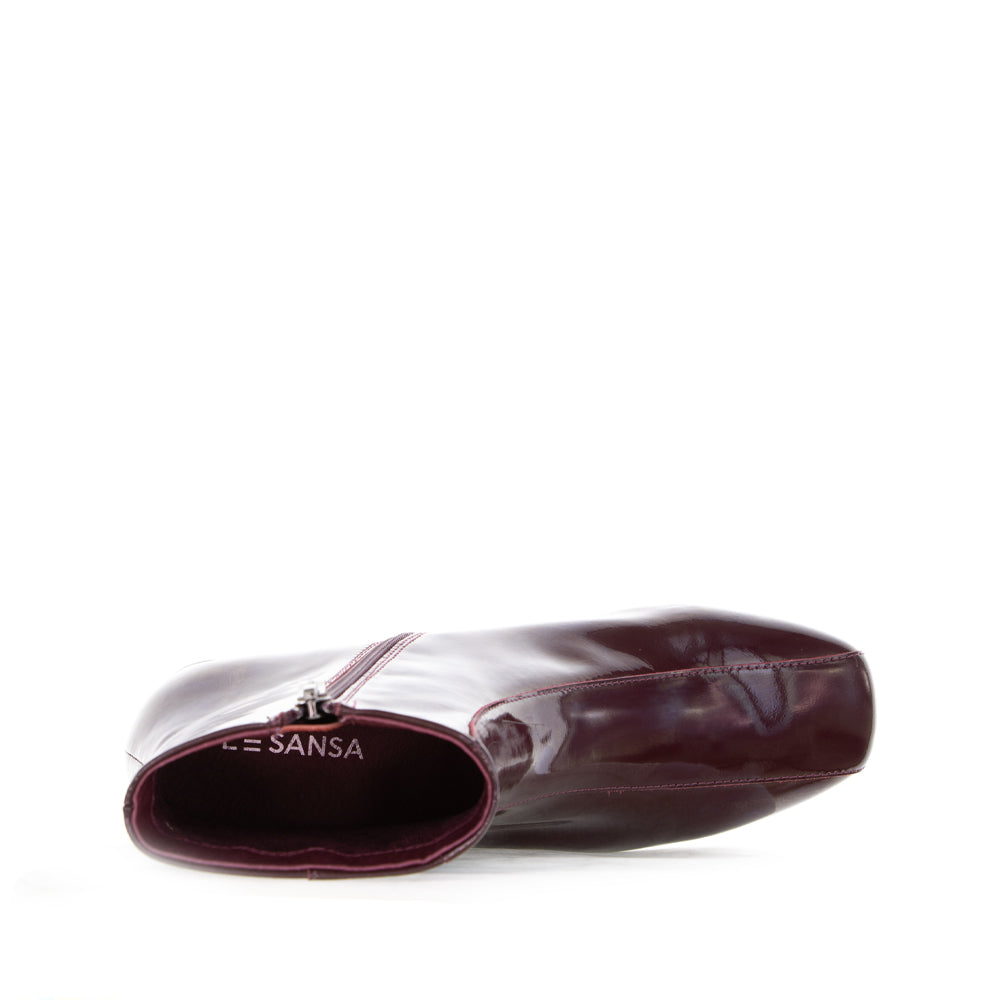 Le Sansa Sasha Merlot Patent Boots featuring sleek, shiny red patent leather with a stylish ankle-high design.