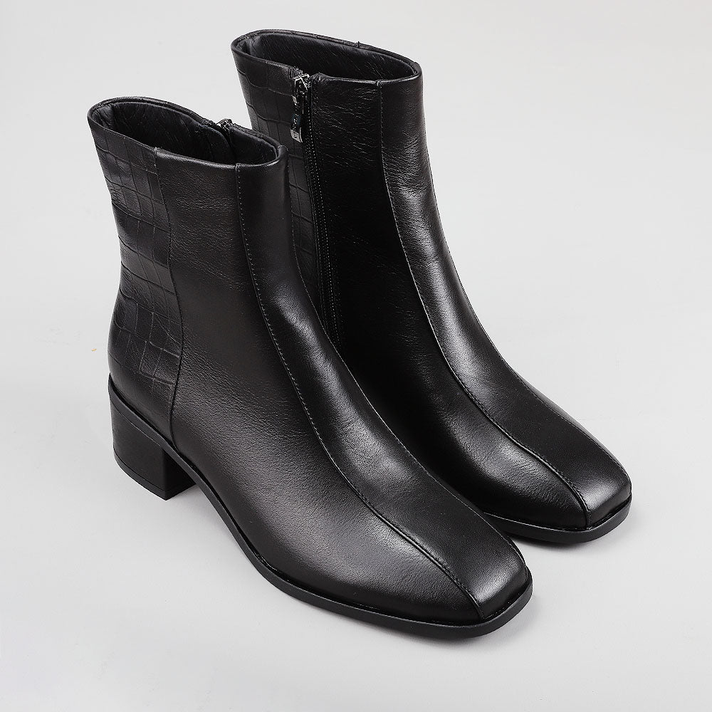 Pair of black Le Sansa Spike boots with textured crocodile print, showcasing their stylish design and chunky sole.