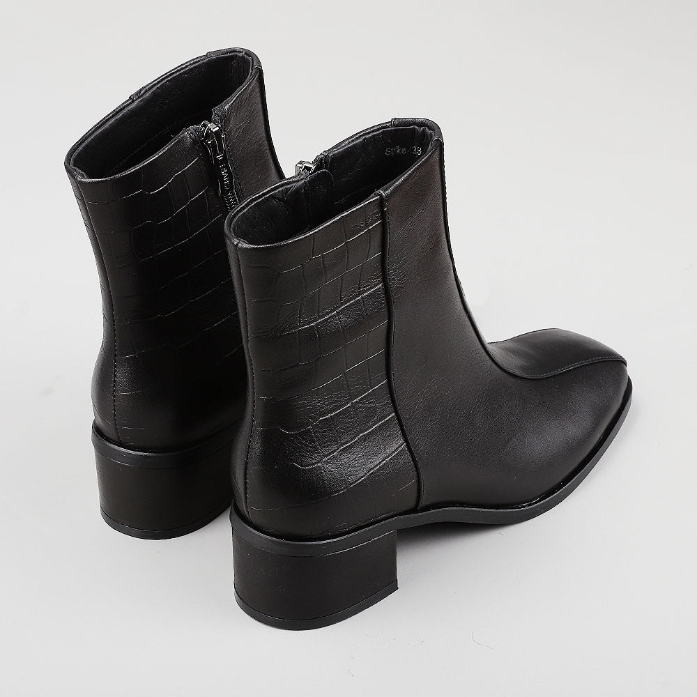 Le Sansa Spike Black boots with black crocodile print, featuring a sleek design and pointed toe, displayed from the back view.