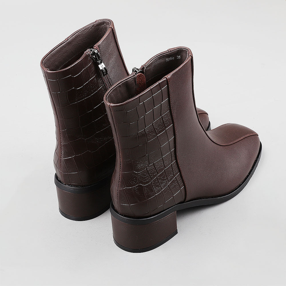 Le Sansa Spike Choco boots with chocolate-colored crocodile print, showcasing stylish, textured footwear.