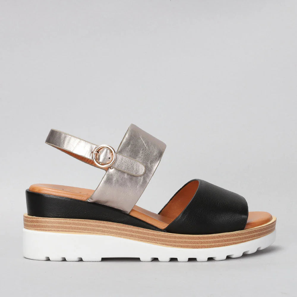 Le Sansa Tess Black Champagne sandals shown from the side, featuring sleek black design with champagne-colored accents.