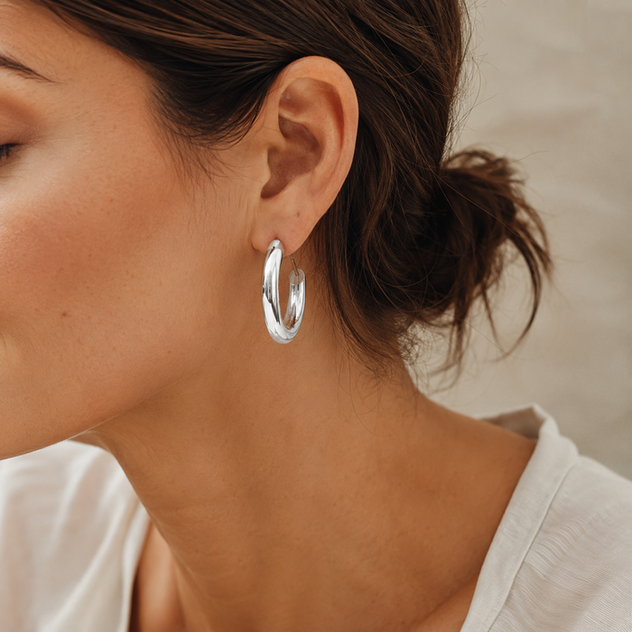 A pair of thick creole earrings from A & C Oslo with bold, rounded metal hoops designed for stylish ear adornment.