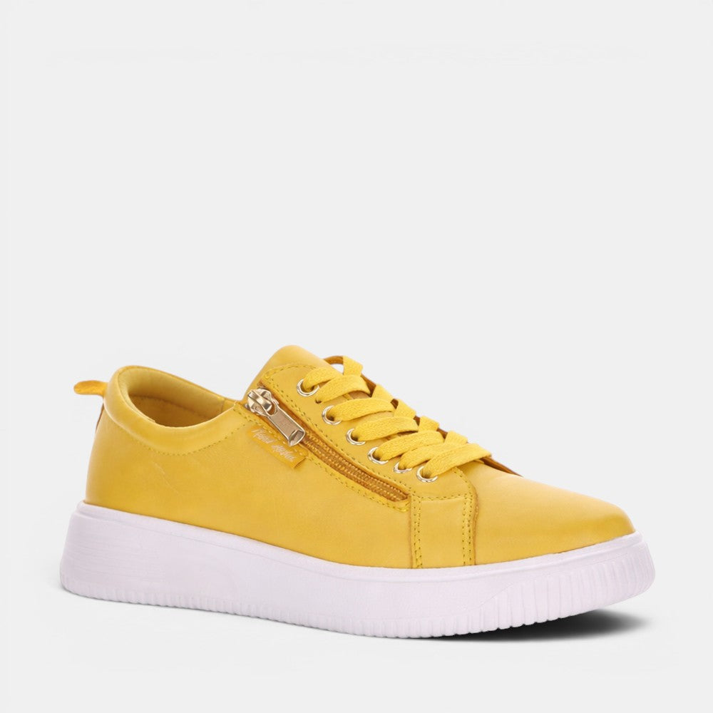 Naked Arches Nelly Mustard sneakers showing mustard yellow canvas upper with white rubber sole and lace-up design.