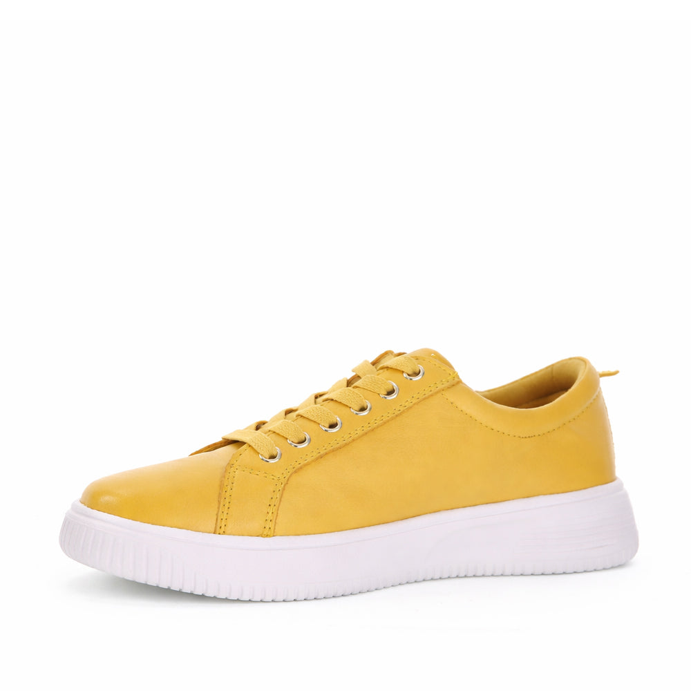 Naked Arches Nelly Mustard sneakers with mustard yellow color and casual lace-up design, displayed on a white background.